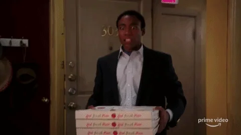 A GIF of a guy walking into a room on fire, holding a pizza